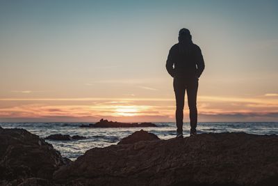 person standing against ocean sunrise